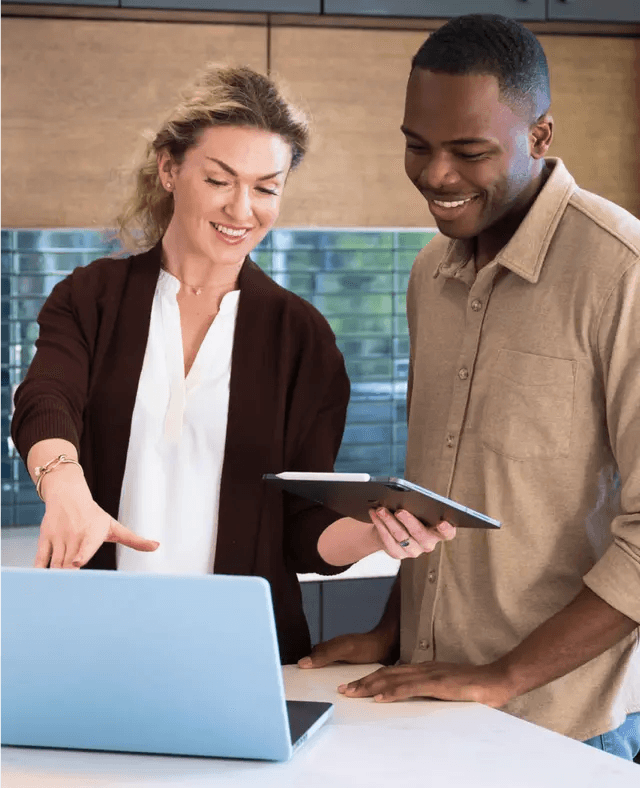 Un homme et une femme sourient en regardant un ordinateur portable.